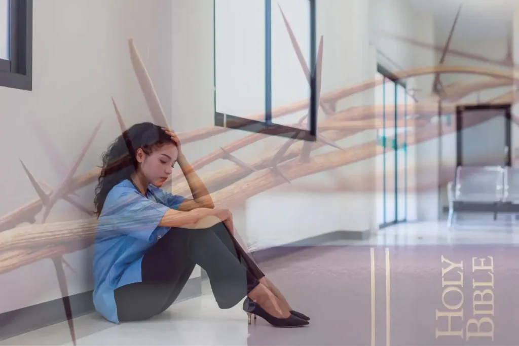A woman sitting, looking worried, in the middle of a hallway, staring down at the ground, turning away from the divine call.